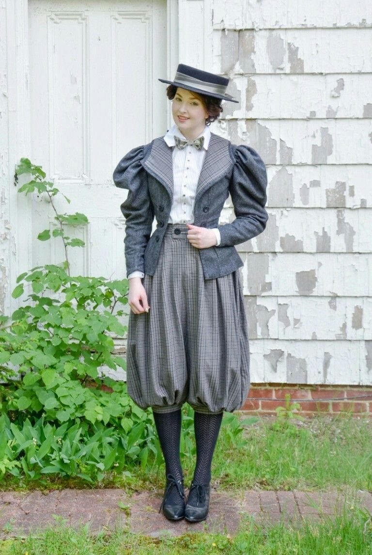 Woman in 19th-century grey pinstriped attire with bloomers and a boater hat.