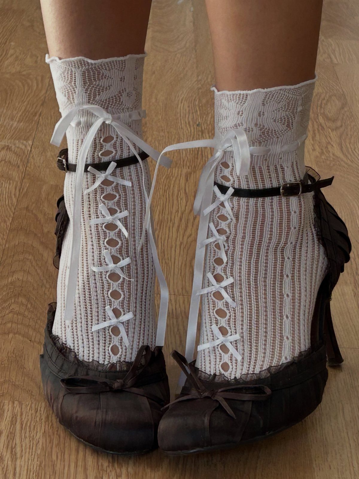 Dark brown satin high heels with bows and white lace ribbon socks.