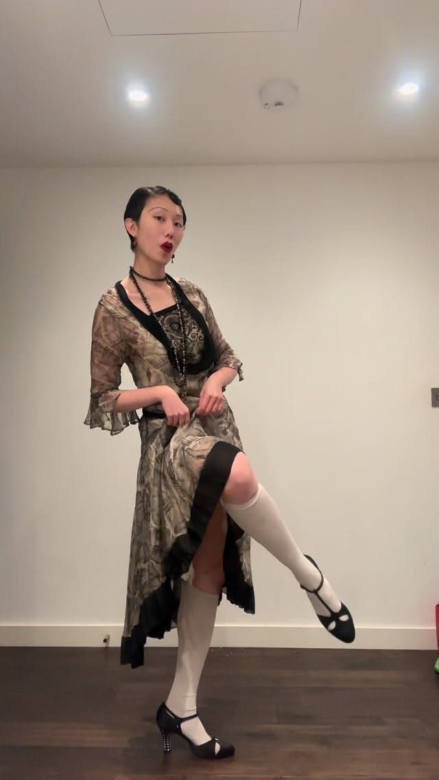 Woman in 1920s dress and white stockings wearing black T-strap high heels
