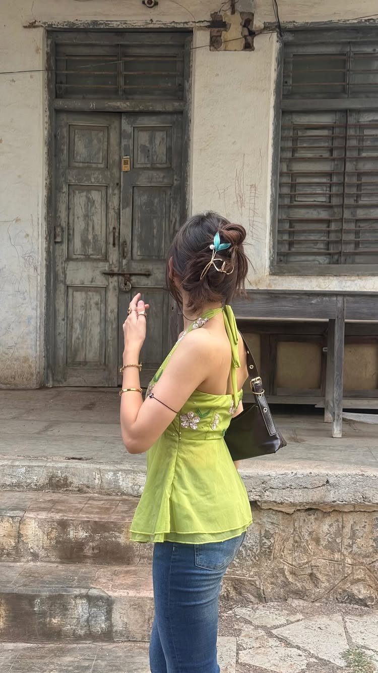 Woman wearing a lime green halter top and blue jeans from behind.