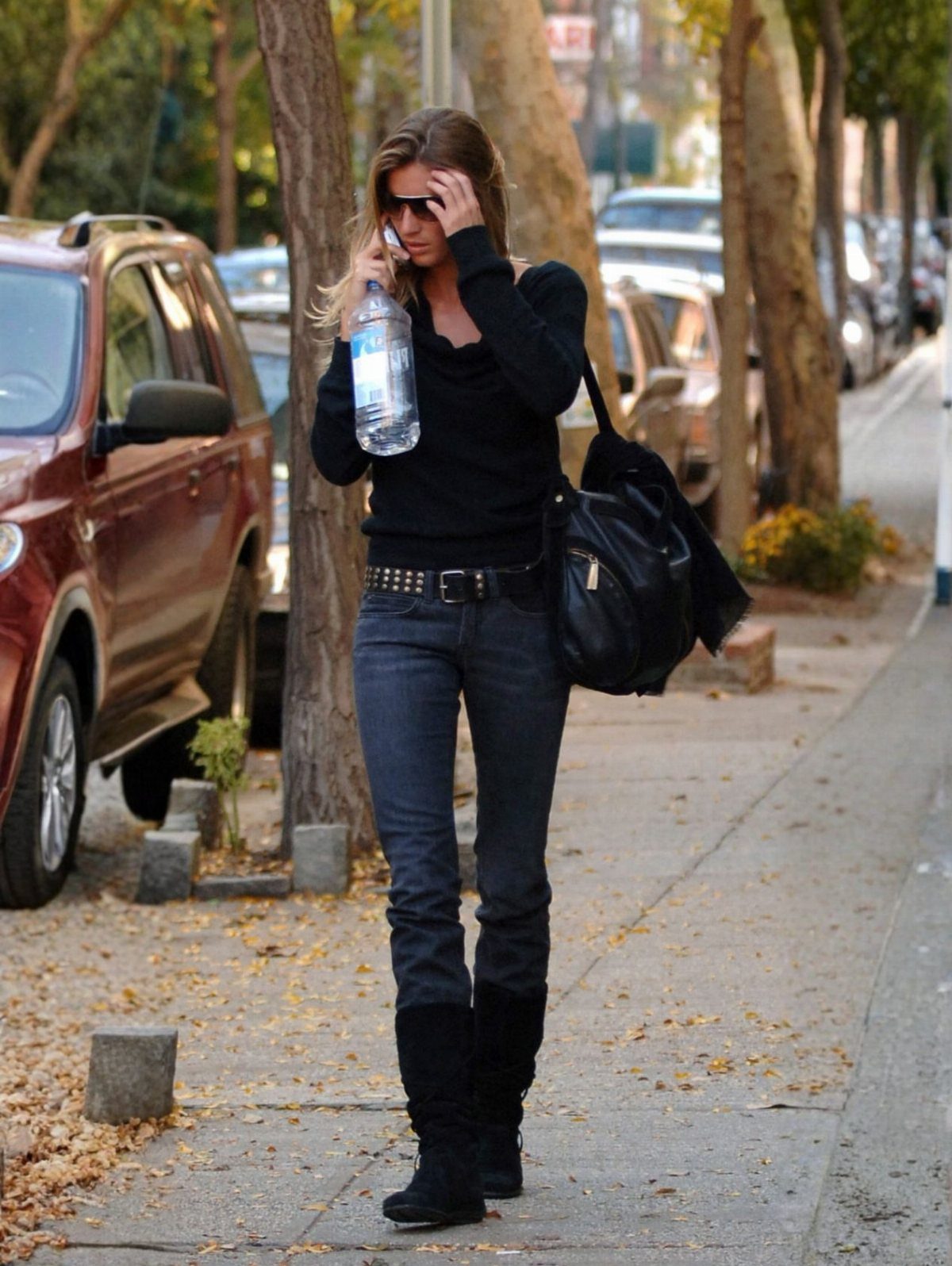 Woman walking on a sidewalk wearing black knee-high boots and dark skinny jeans.