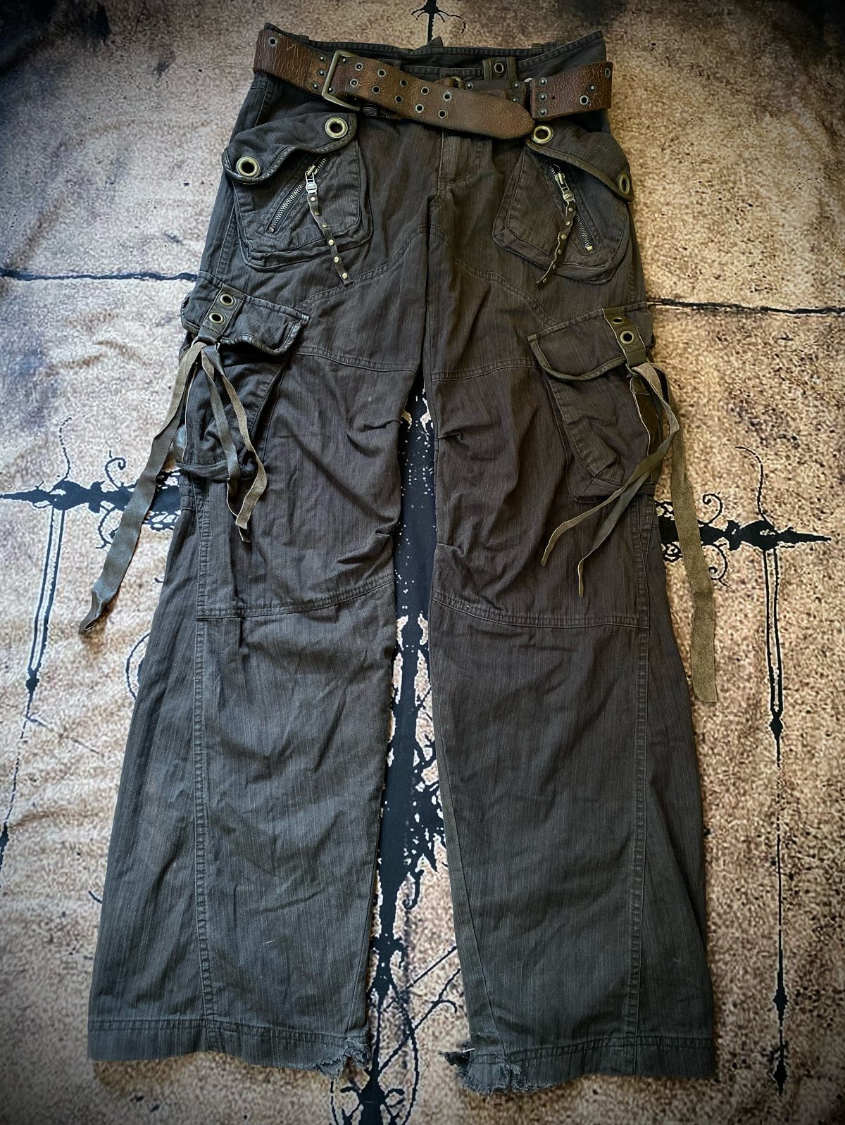 Dark olive green baggy cargo pants with straps and a brown leather belt.