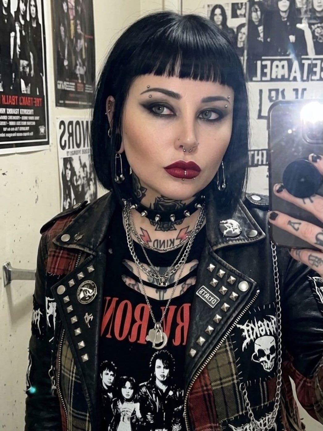 Woman in emo punk fashion wearing a studded leather jacket and layered necklaces.