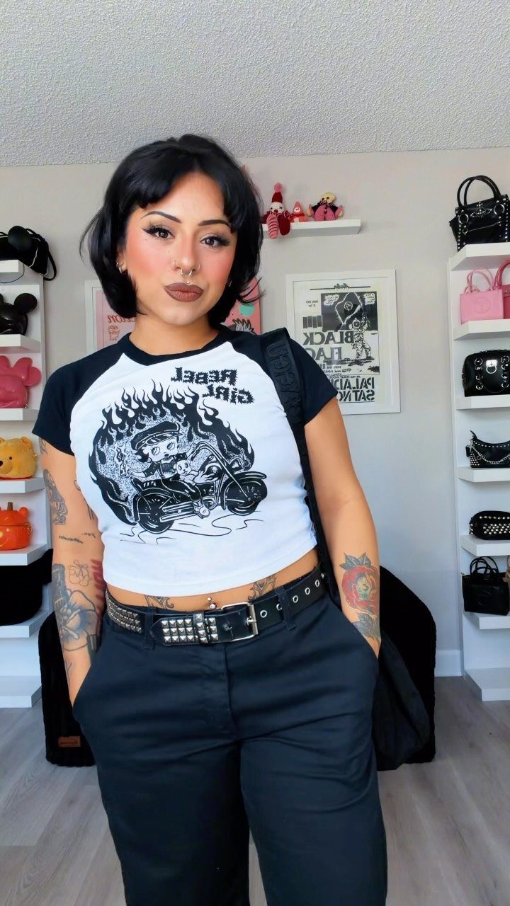 Woman wearing a white raglan graphic tee with a motorcycle and studded belt.
