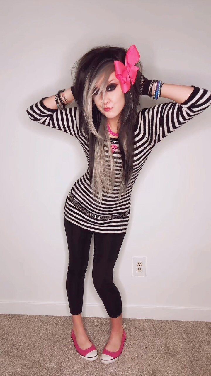 Person in pop punk style wearing striped shirt, pink bow, and pink shoes.