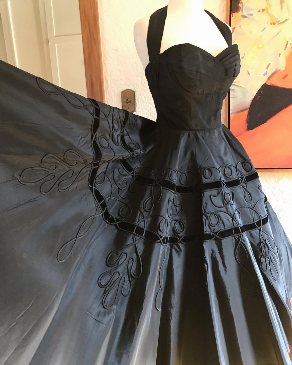 Black vintage halter dress with embroidered full skirt displayed on a white mannequin