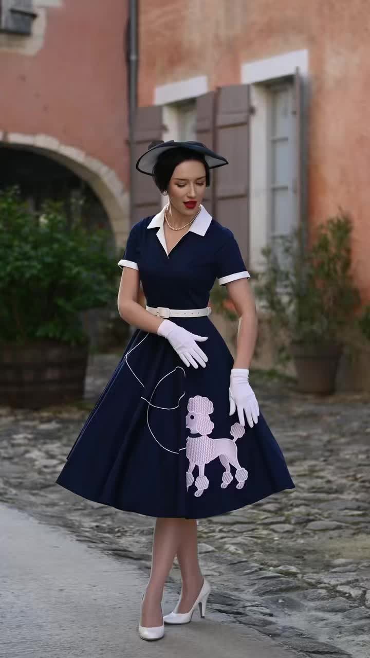 Woman in navy blue 1950s shirtwaist dress with white poodle applique and accessories.