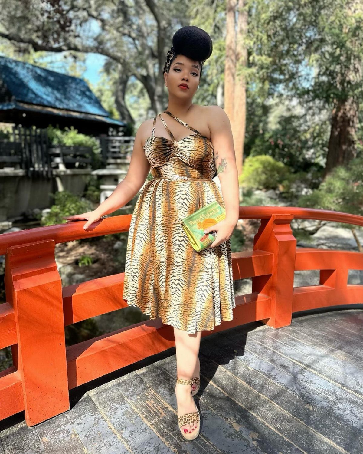 Woman in tiger print 1950s style party dress posing on a red bridge