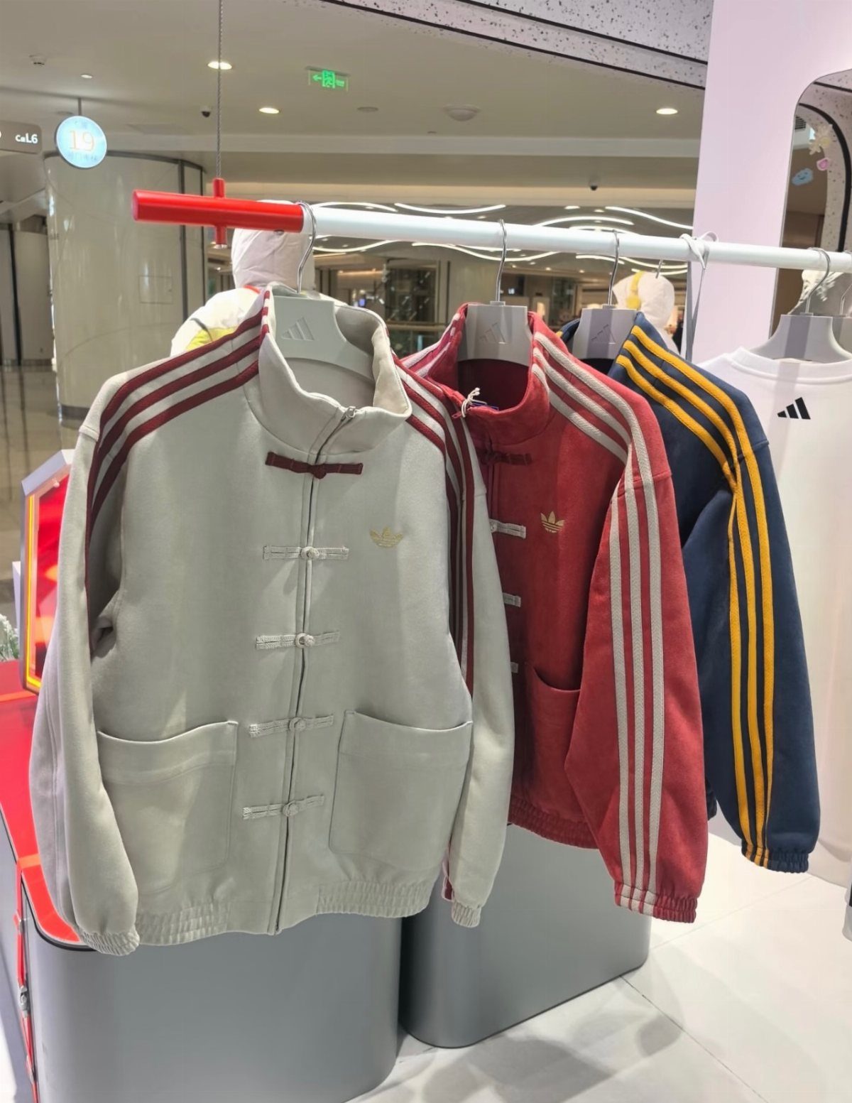 Adidas jackets with frog button closures in cream, red, and navy blue colors.
