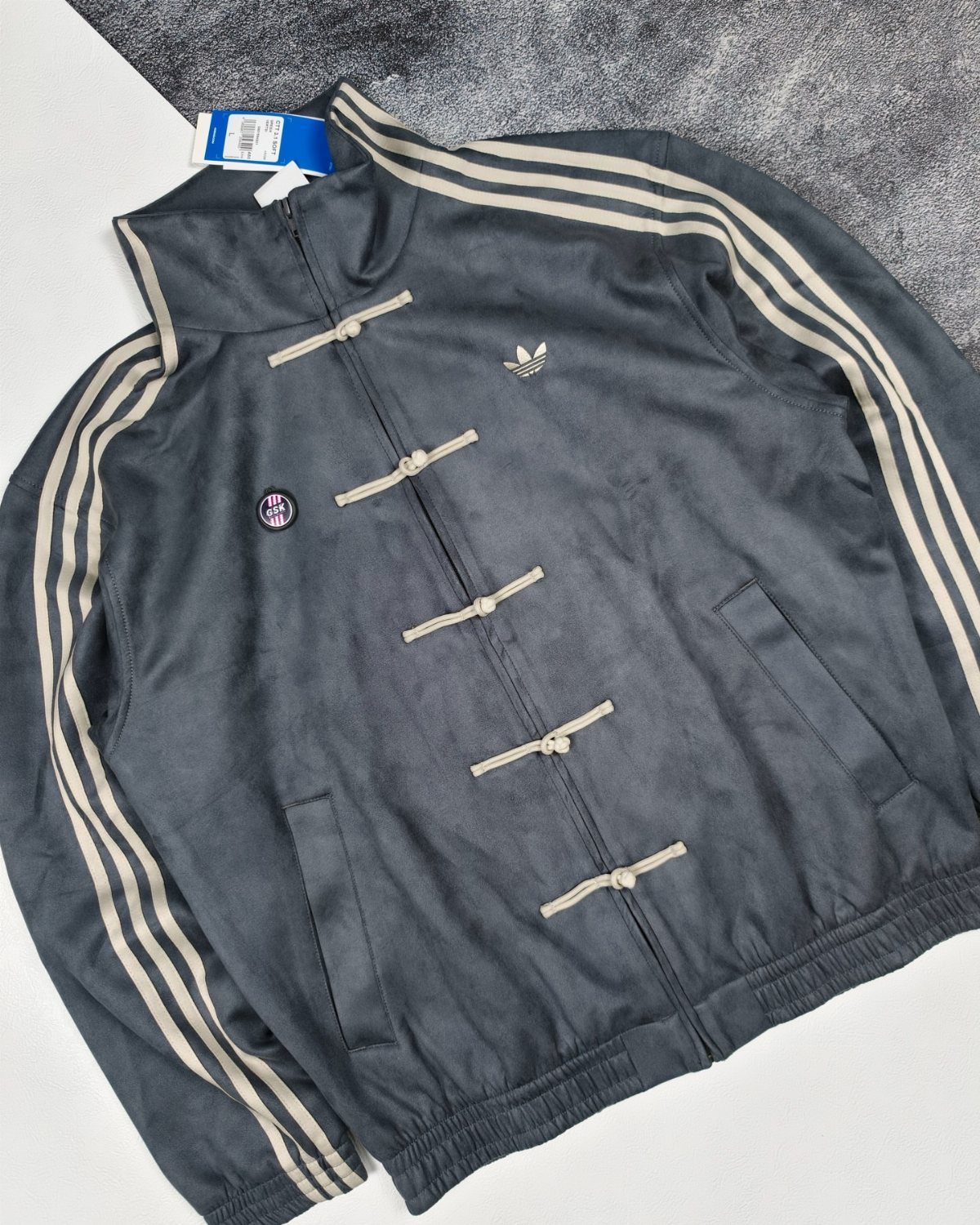 Dark grey Adidas track jacket featuring traditional Chinese frog button closures and white stripes.