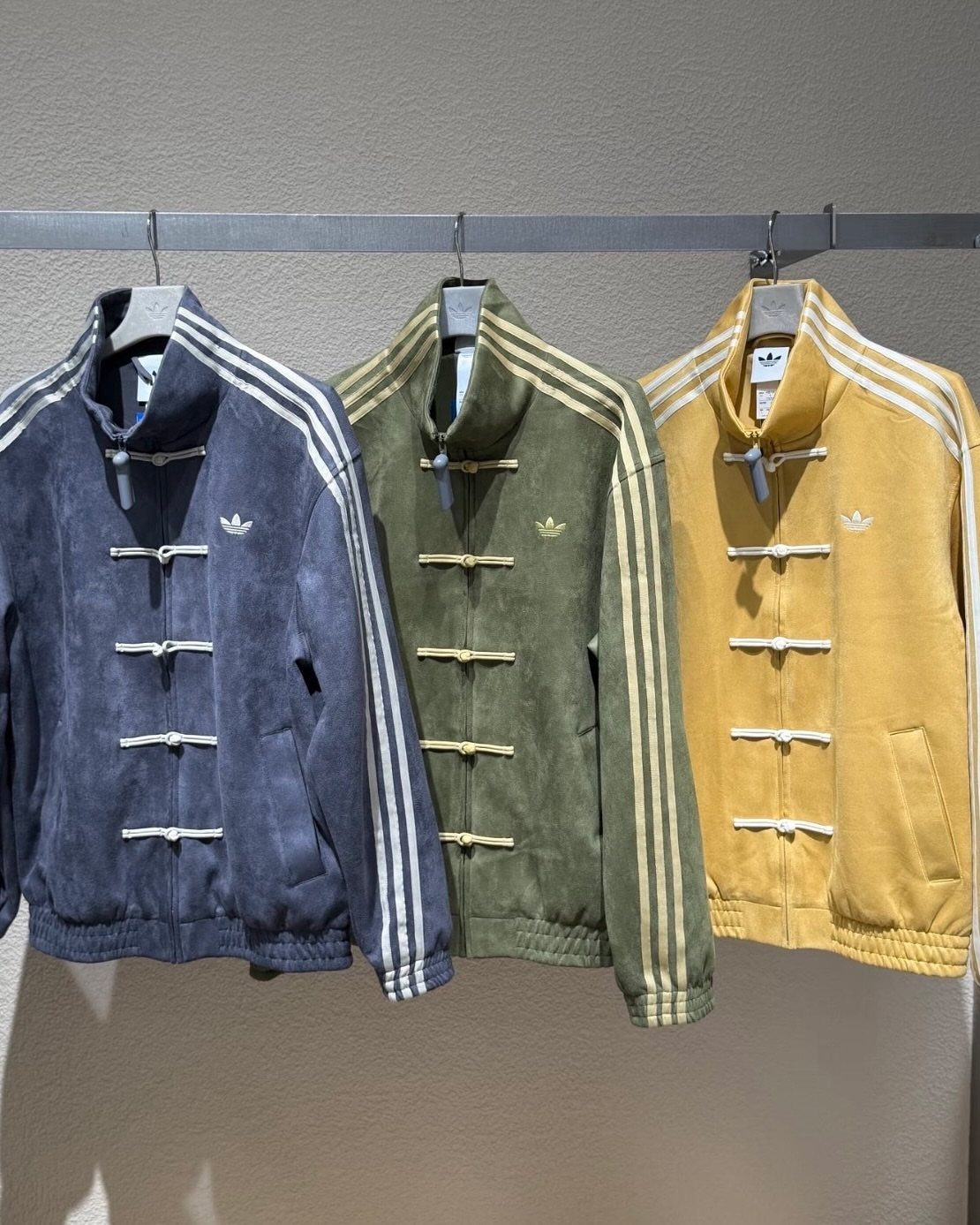 Three Adidas jackets with mandarin collars and frog buttons in blue, green, and yellow.