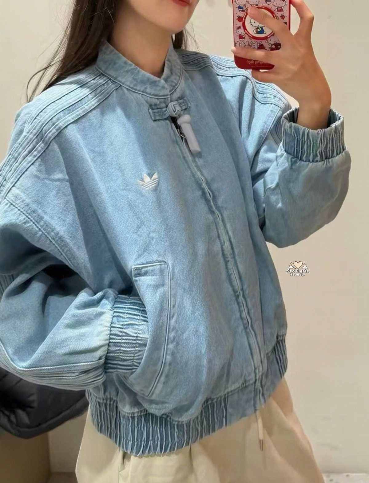 Person wearing a light blue denim Adidas jacket and cream pants in mirror selfie
