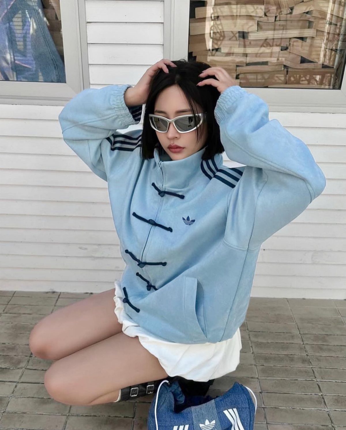 Woman wearing a light blue Adidas jacket with traditional Chinese frog button closures.