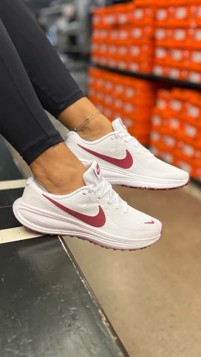 White Nike running shoes with maroon swooshes worn by a person in leggings.
