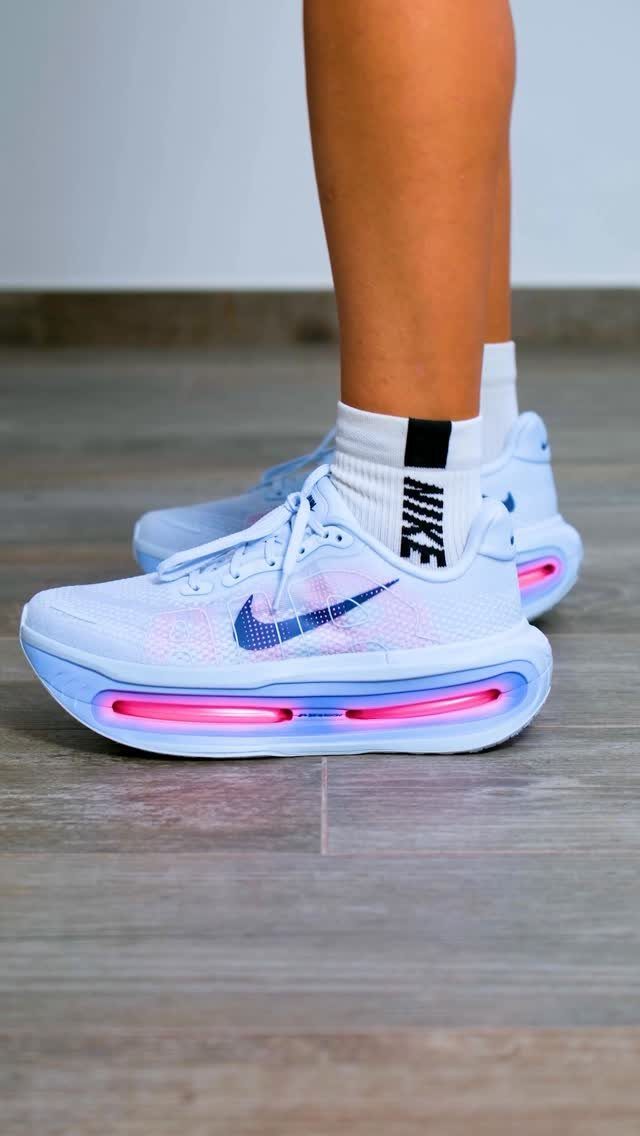 Light blue Nike running shoes with glowing pink soles on a wooden floor