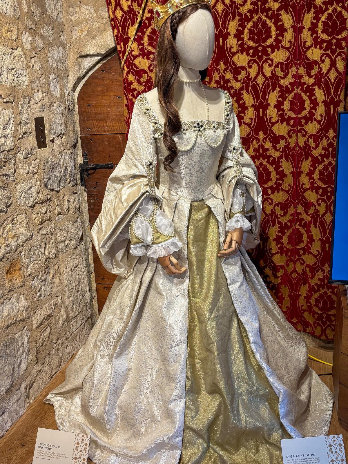 Tudor-style gown in white and gold on a mannequin with a gold crown.