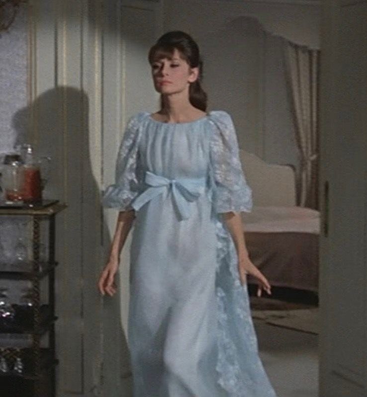 Audrey Hepburn wearing a light blue lace gown with a bow at the waist.