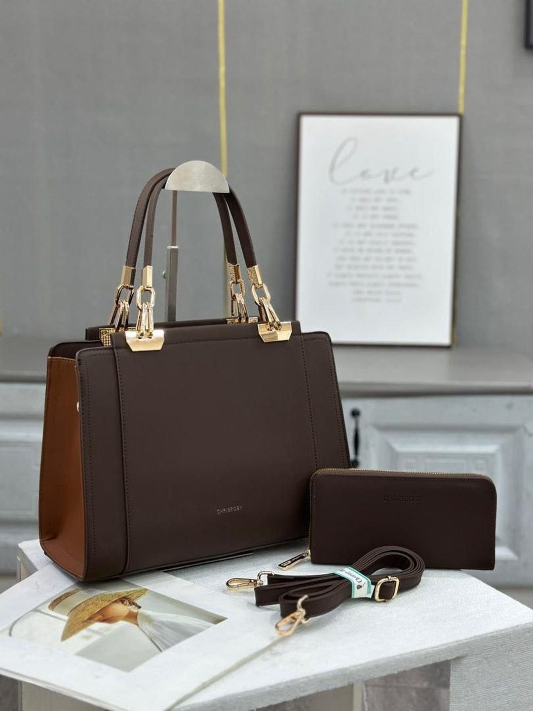 Dark brown structured leather handbag with gold hardware and matching wallet on marble.