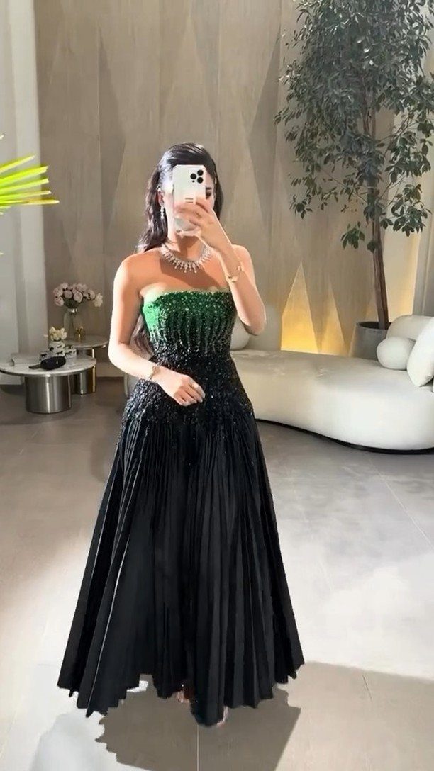 8 Beaded Formal Dress Ideas for Every Color and Style 5 Woman in a strapless gown with a green beaded bodice and black skirt.