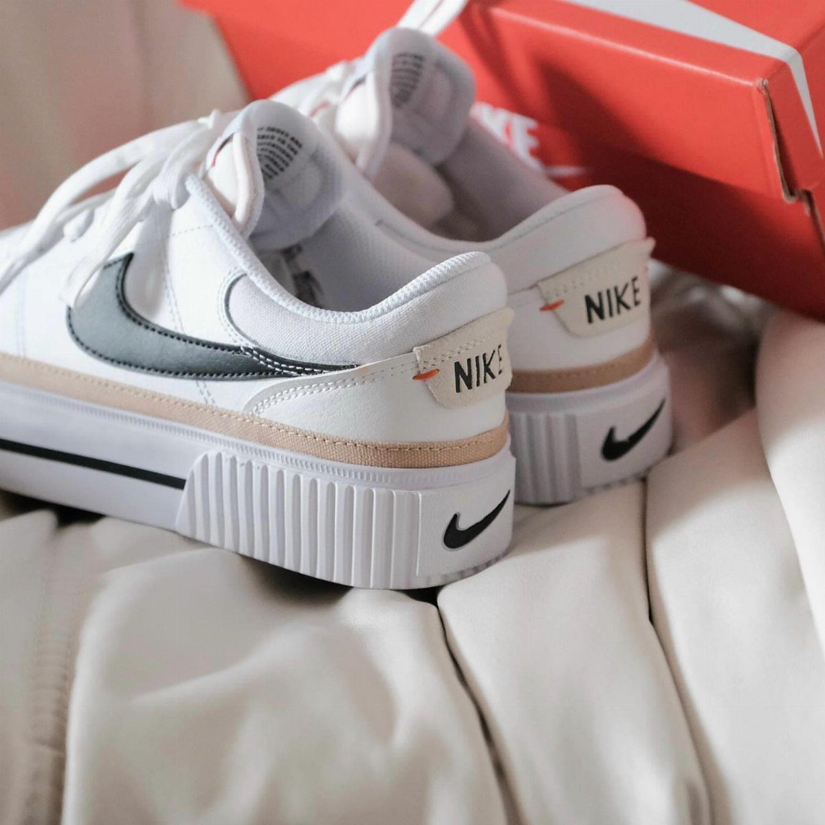 White Nike Court Vision sneakers with beige accents on white quilted fabric.