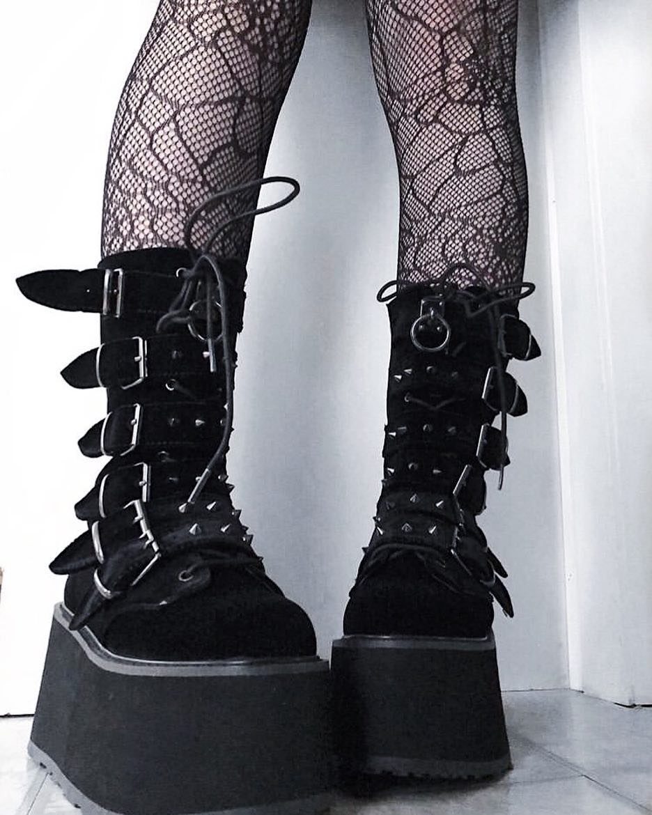 Black platform boots with buckle straps and spikes worn with fishnet stockings.