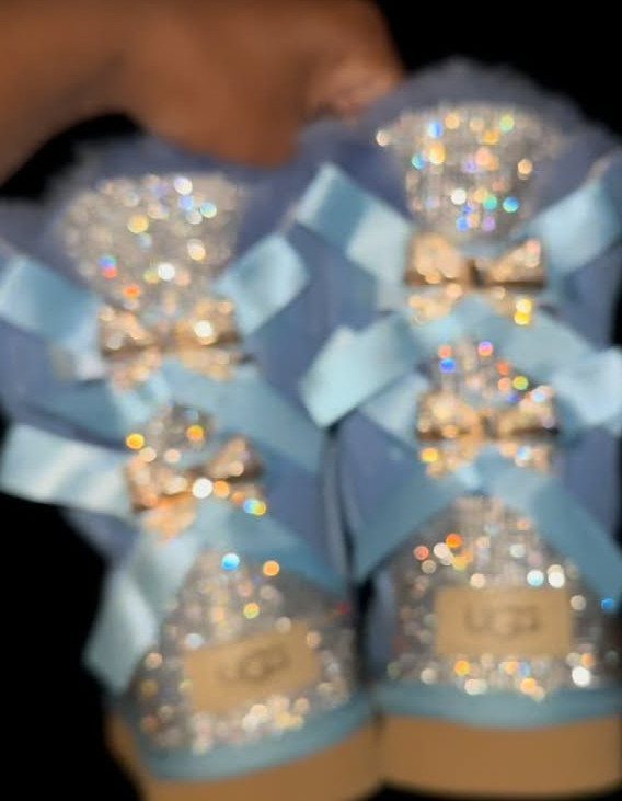 Light blue UGG boots covered in rhinestones with satin ribbon bows.