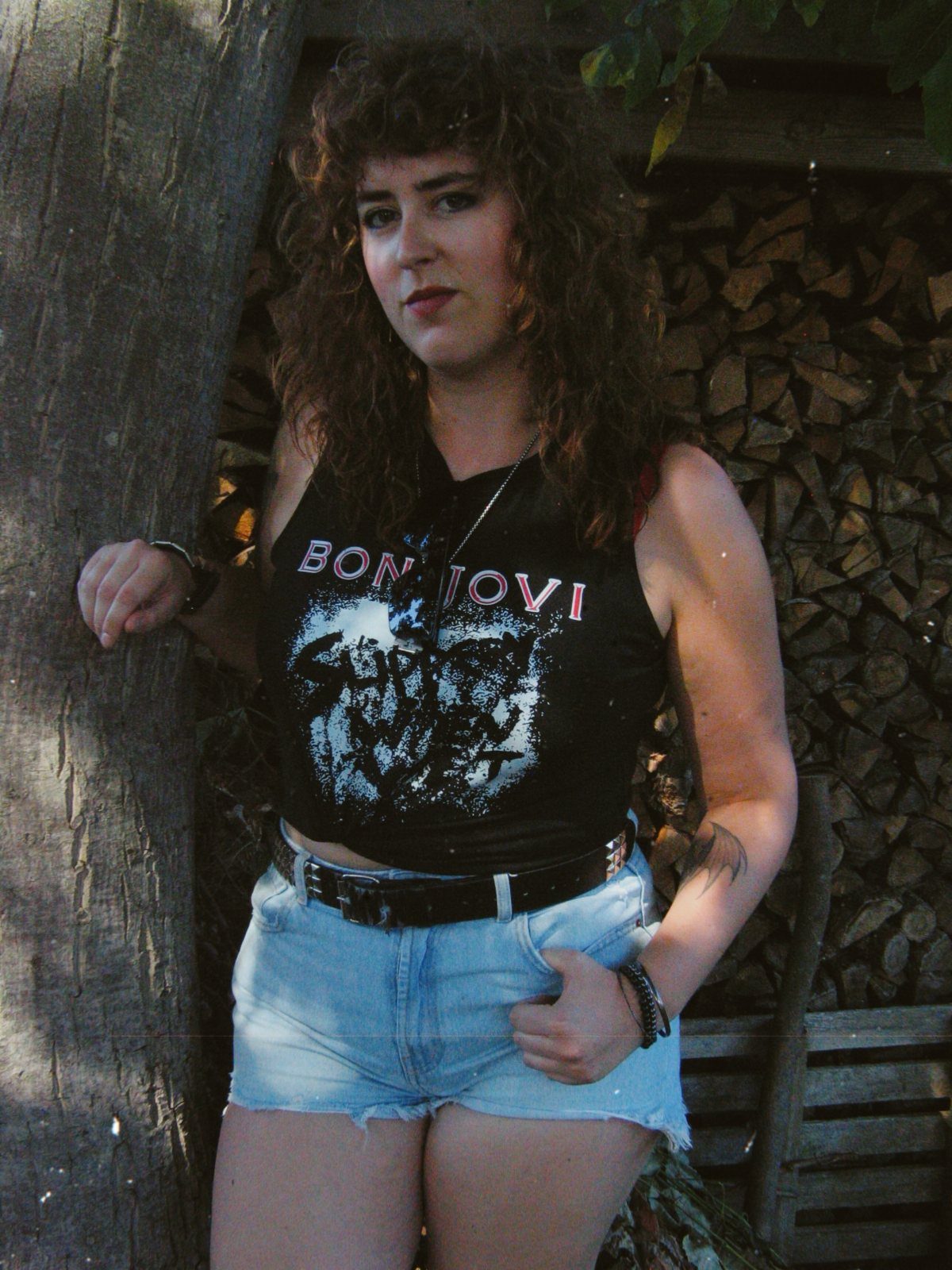 Woman wearing a black Bon Jovi graphic tank top and light blue denim shorts.