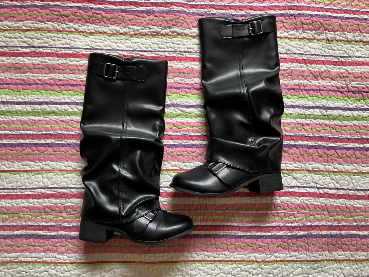 Black mid-calf boots with silver buckles on a colorful striped fabric background.