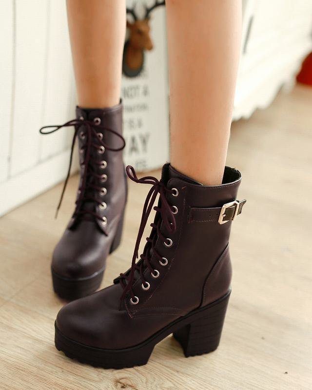 Dark burgundy ankle boots with laces and buckle straps on a wooden floor