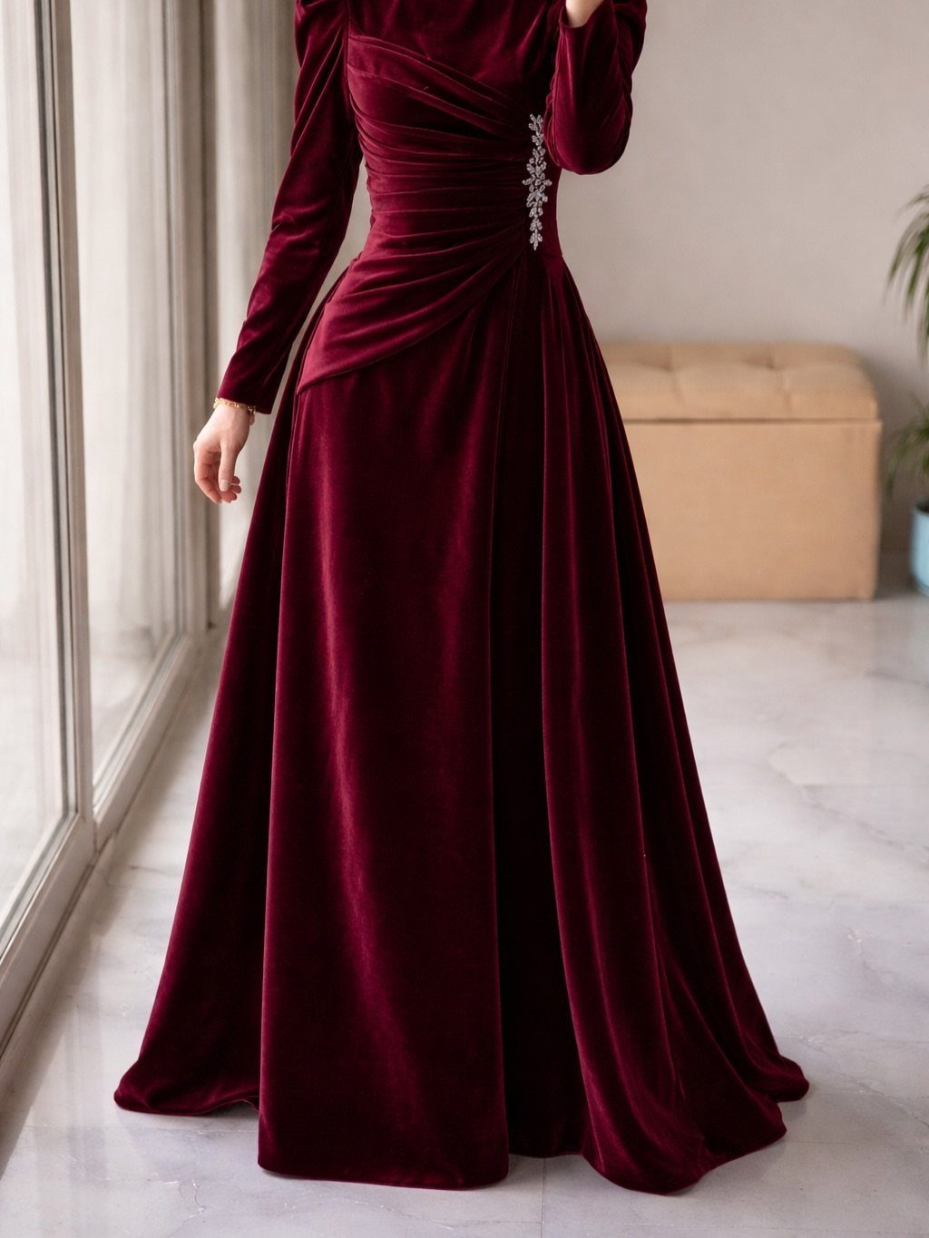 Burgundy velvet long sleeve gown with ruched waist and rhinestone detail.