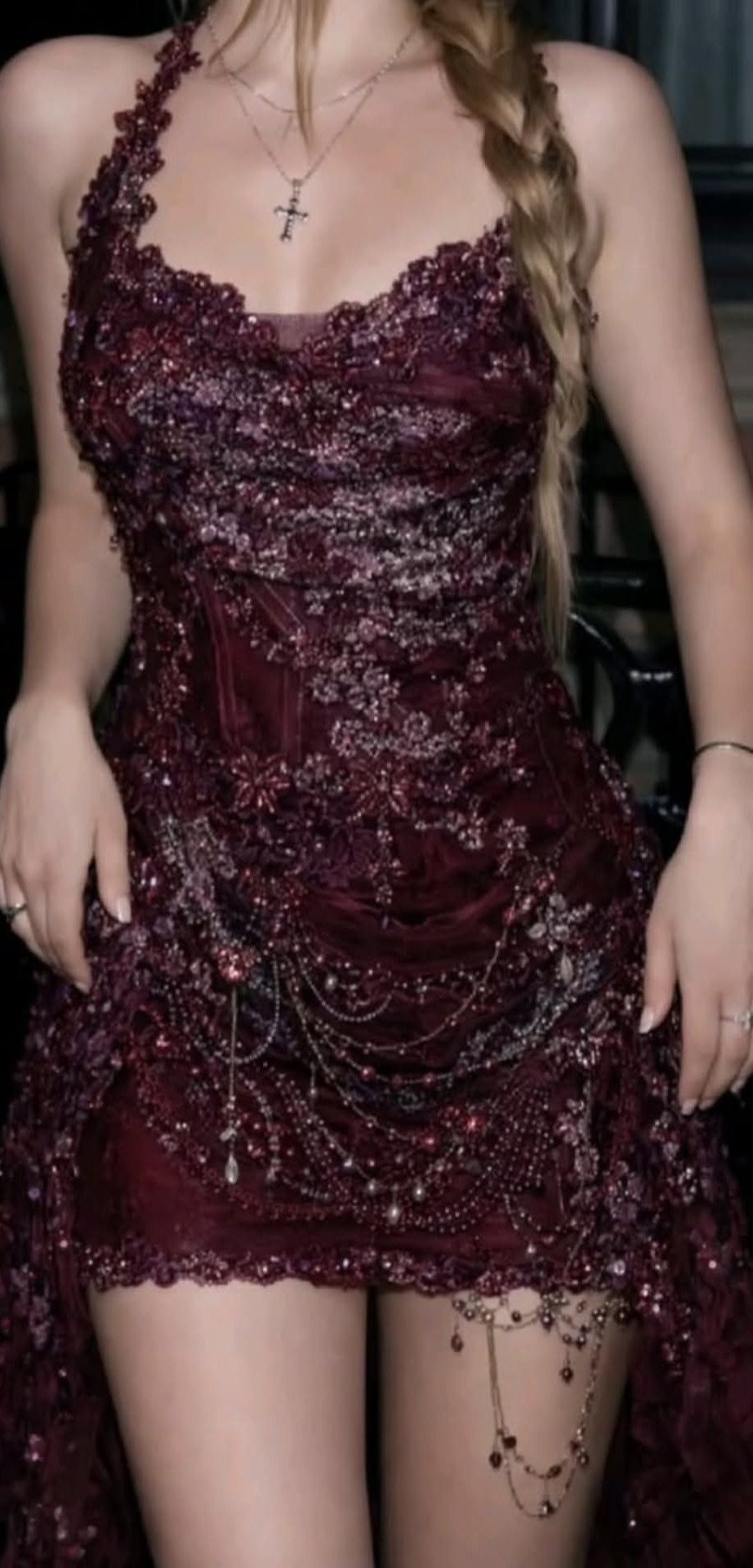 Person wearing a short burgundy dress with sequins and hanging metallic chain details.