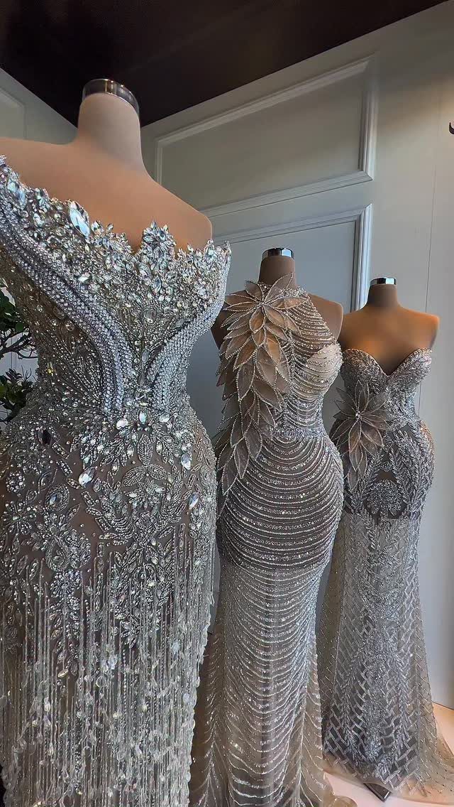Three silver sequined gowns on mannequins with fitted bodices and shimmering details.