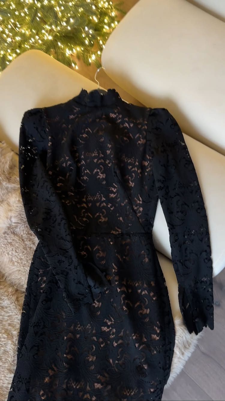 Black lace dress with long sleeves and high neck on beige background