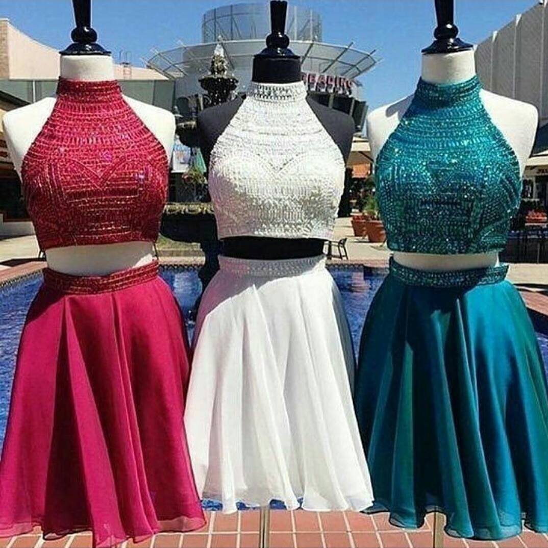 Three two-piece homecoming dresses in red, white, and teal on mannequins outdoors.