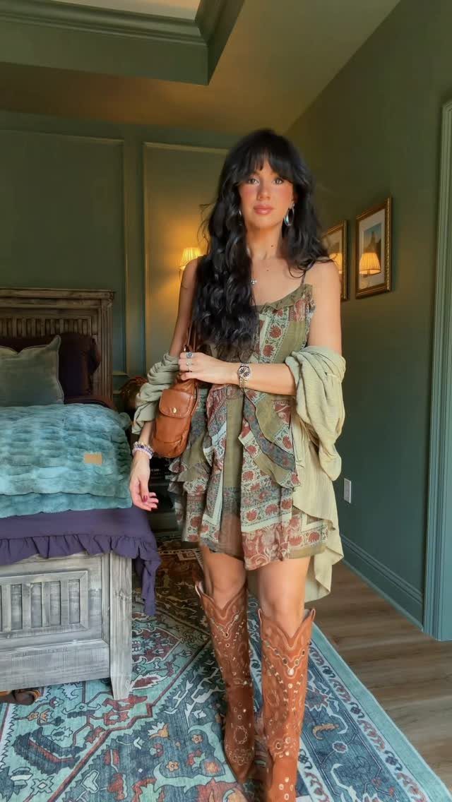 Woman wearing a patterned olive green boho dress and brown cowboy boots.