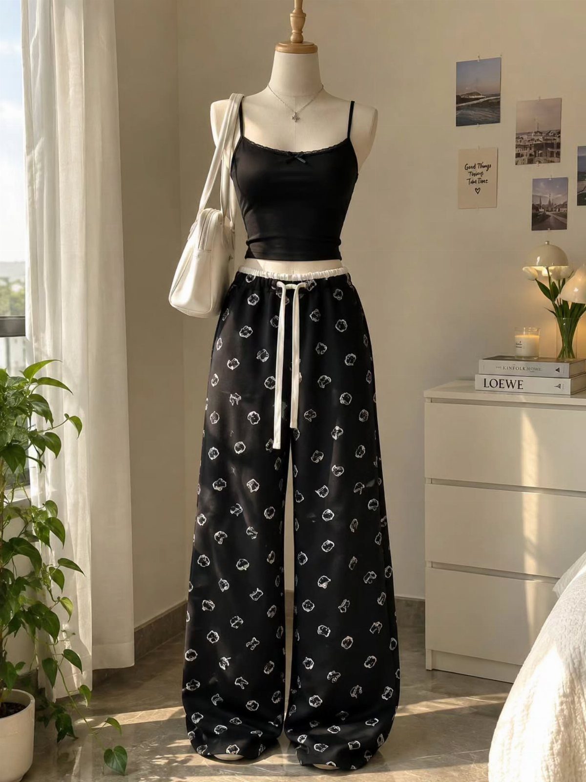 Mannequin wearing a black crop top and wide-leg floral print trousers with white handbag.