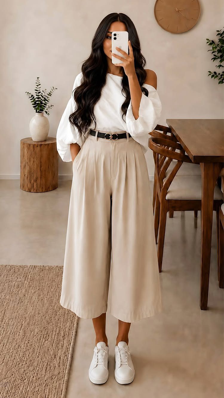Woman wearing a white blouse and beige wide-leg trousers in a modern room