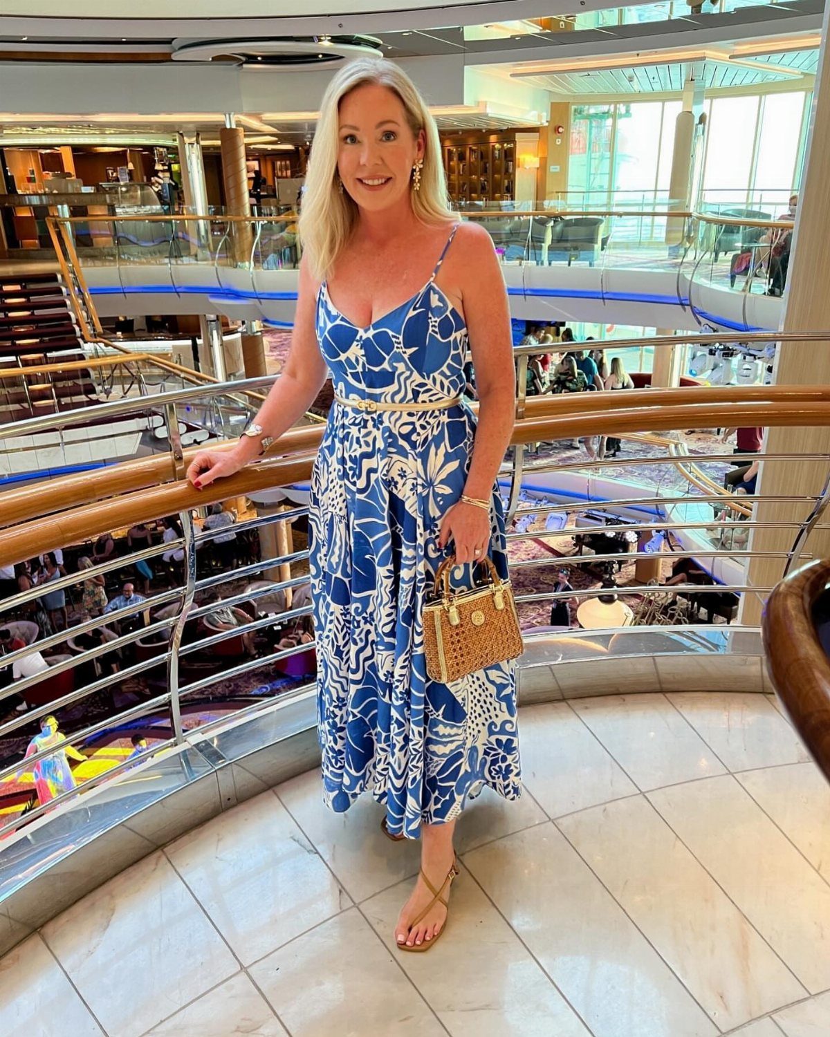 Woman in blue and white floral midi dress standing on a cruise ship deck