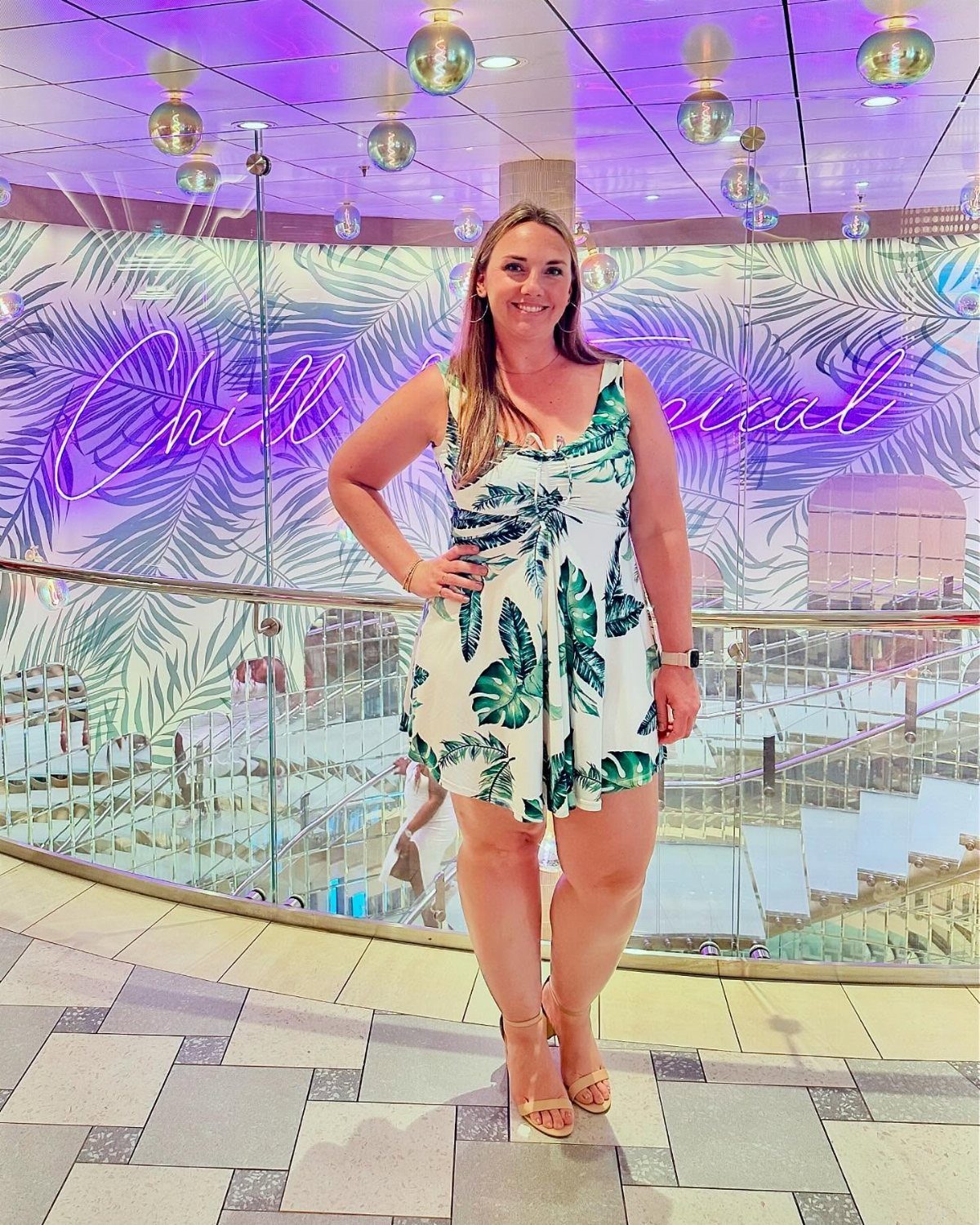 Woman in a tropical leaf print white dress posing in a cruise ship lounge