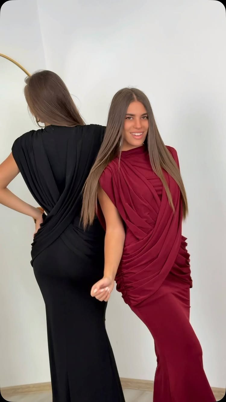 Two women wearing long, draped gowns in black and burgundy colors.