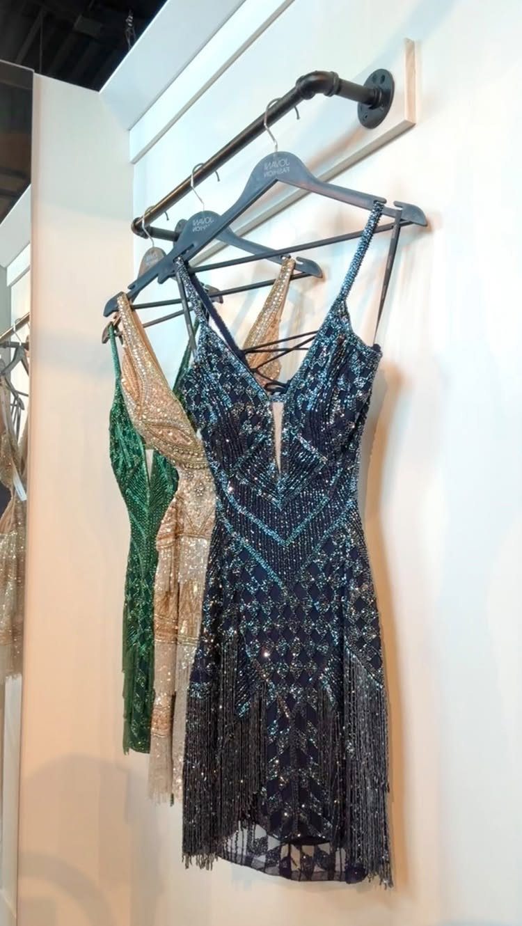 Dark blue sequined cocktail dress with a fringe hem hanging on a rack