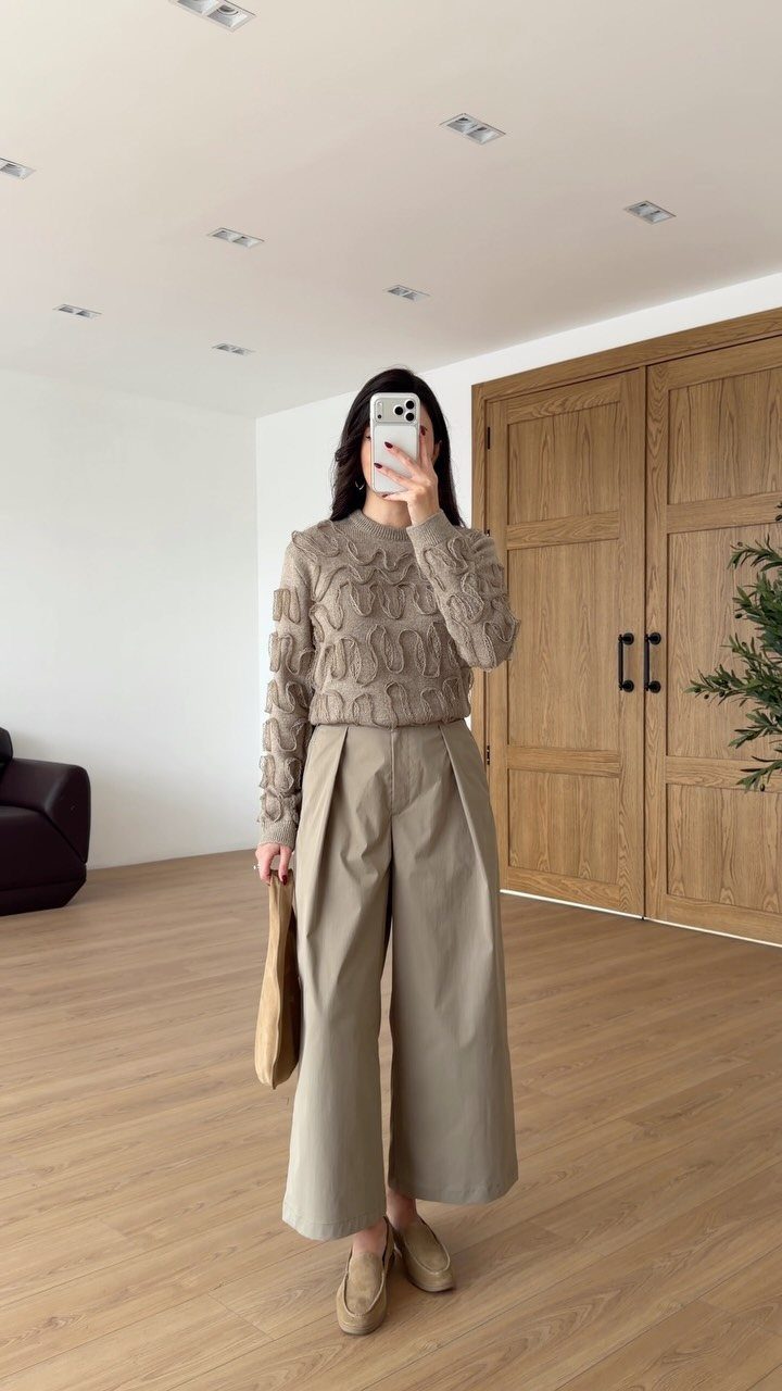 Woman wearing a monochromatic beige outfit with a textured knit sweater and wide-leg trousers.