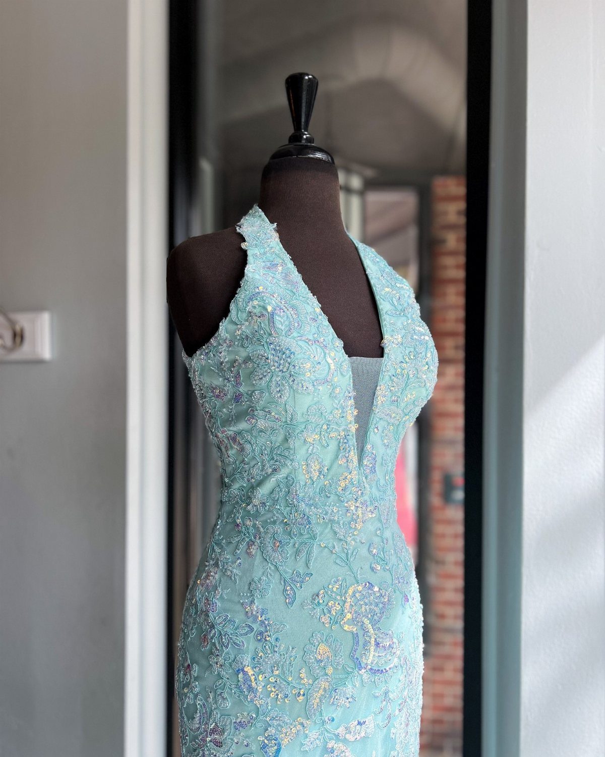 Light blue beaded V-neck dress on a mannequin in a doorway