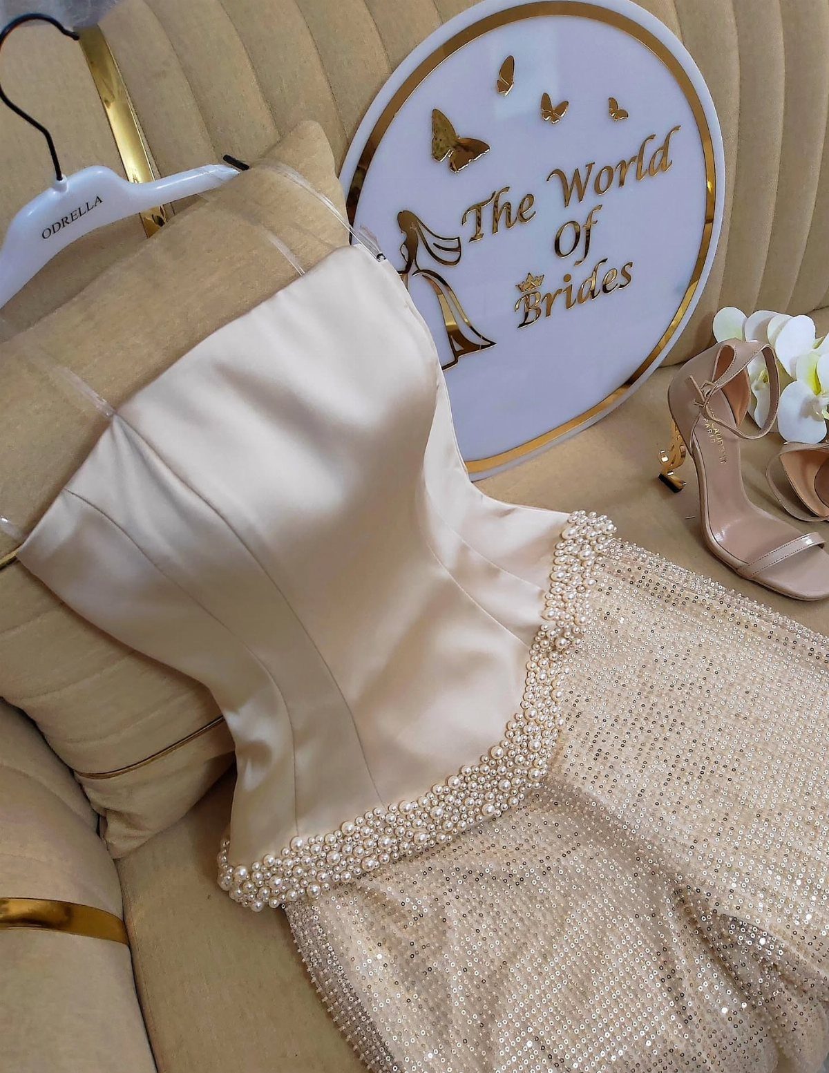 Champagne strapless dress with beaded skirt and satin bodice on a beige cushion.