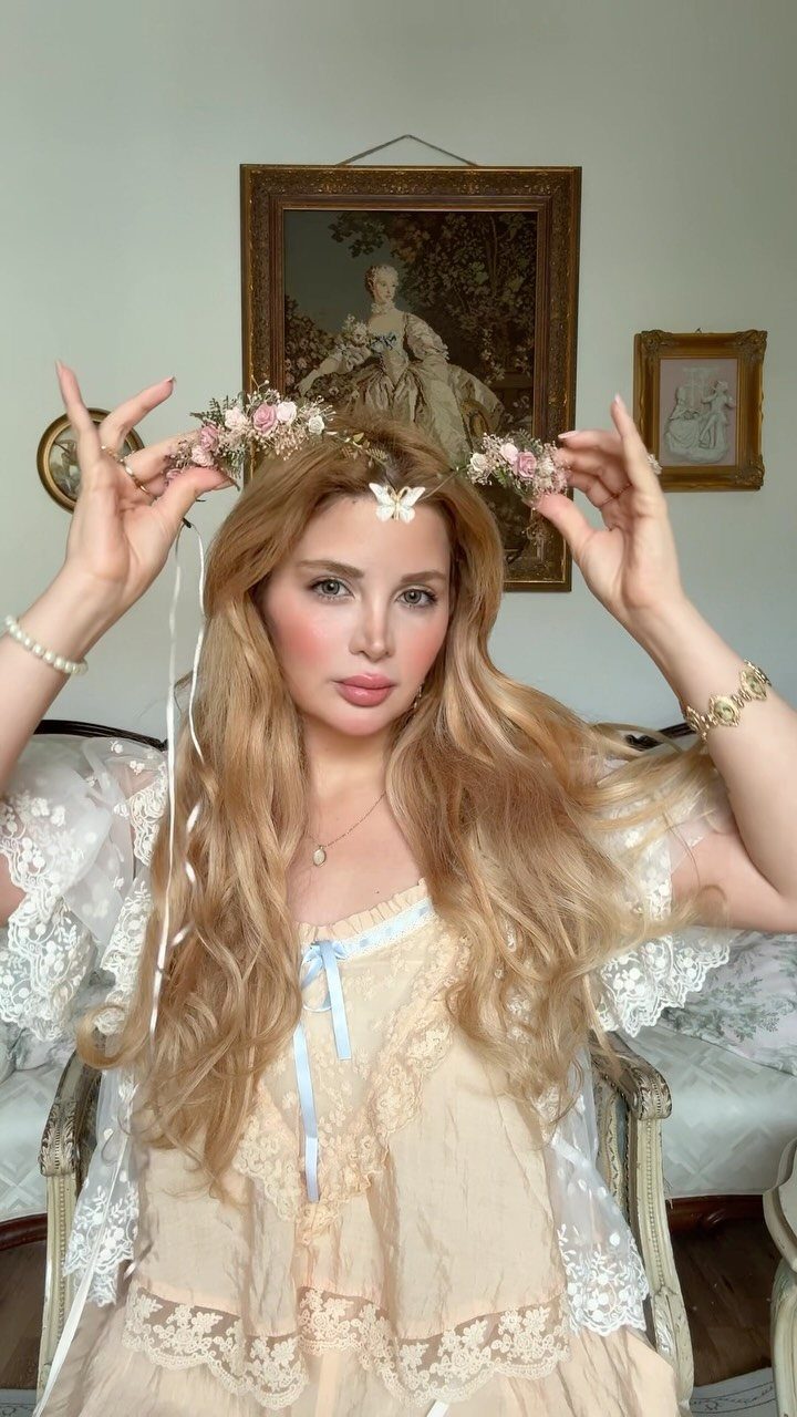 Woman with blonde hair wearing a delicate pink and white flower crown.