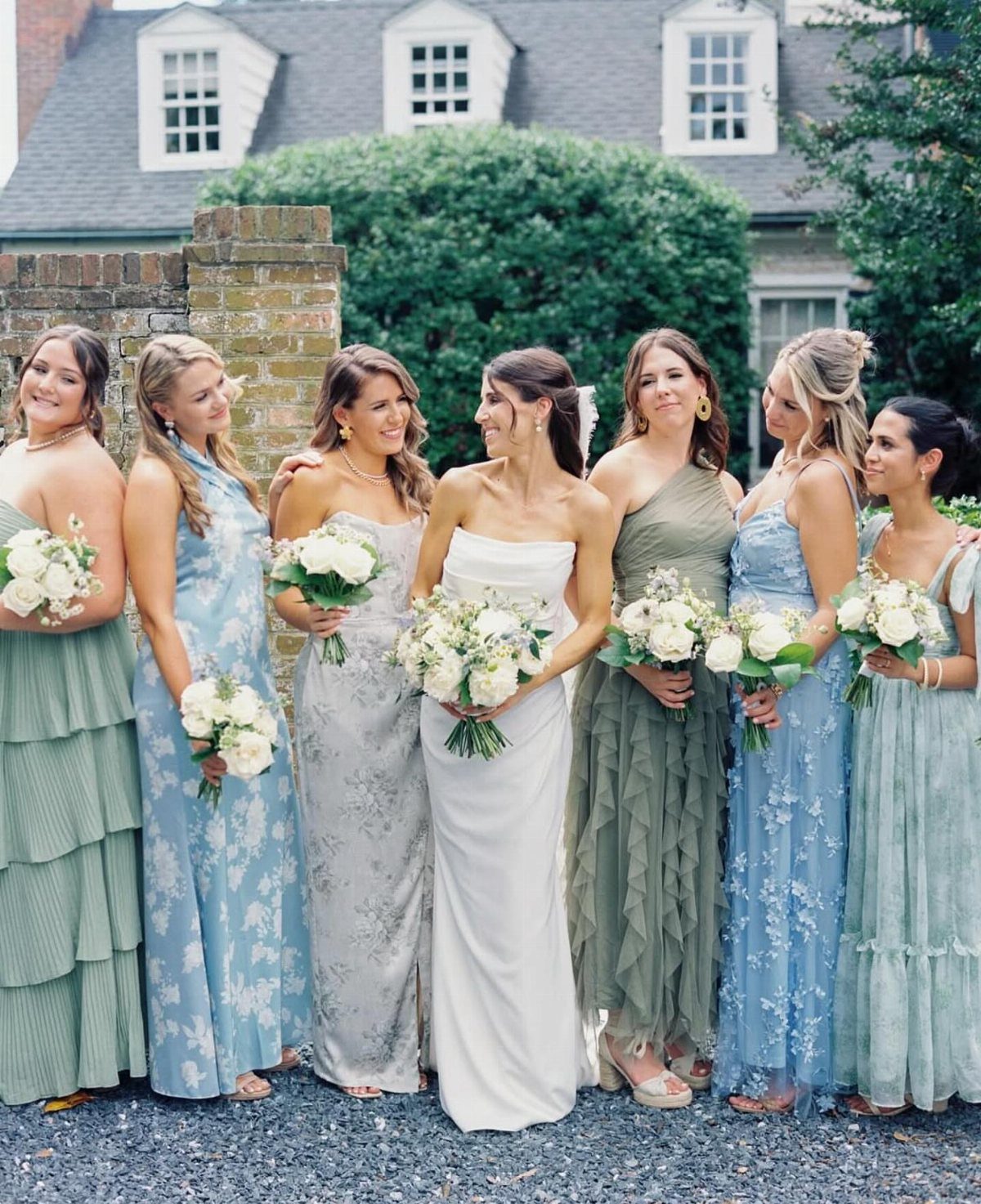 Bride and bridesmaids wearing mix-and-match dresses in sage green and light blue tones.