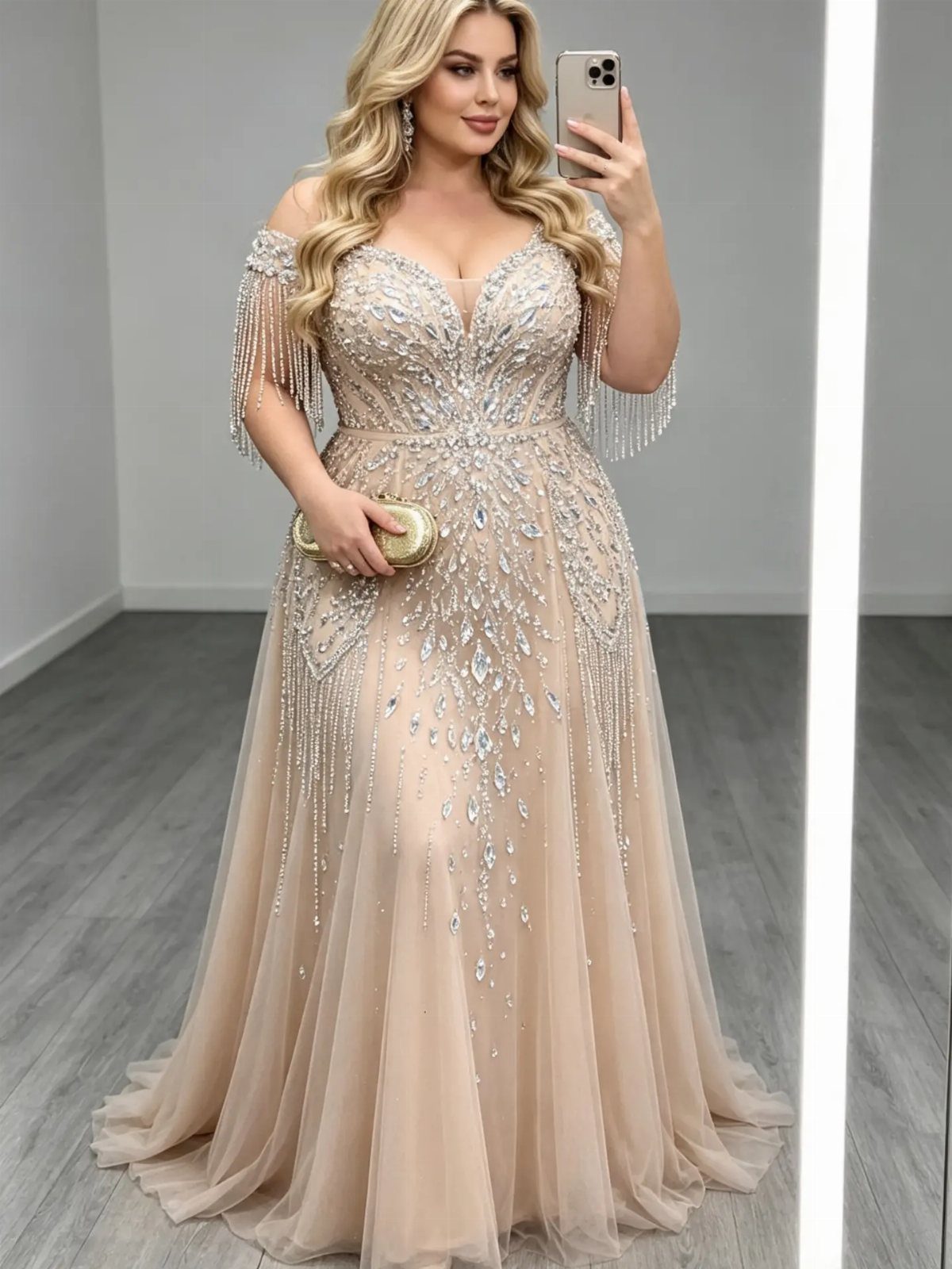 Woman in a champagne beaded gown with fringed sleeves taking a mirror selfie.