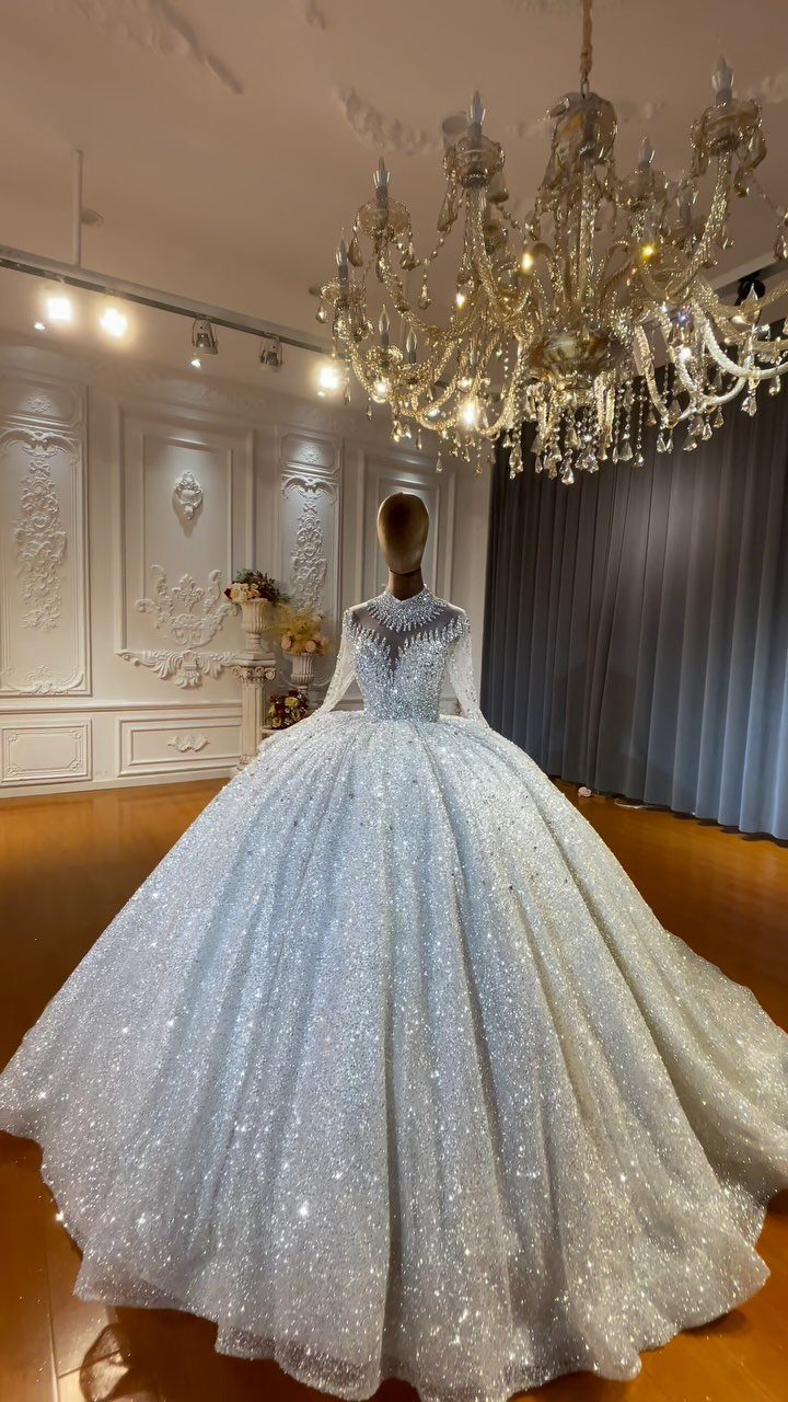 Sparkling white ball gown wedding dress on a mannequin under a crystal chandelier.