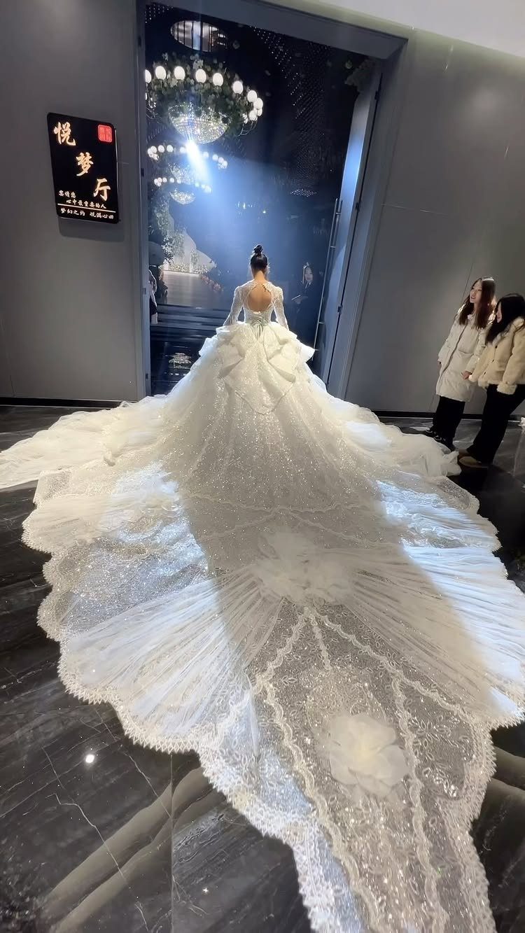 Woman wearing a giant white wedding dress with a massive, sparkling train.