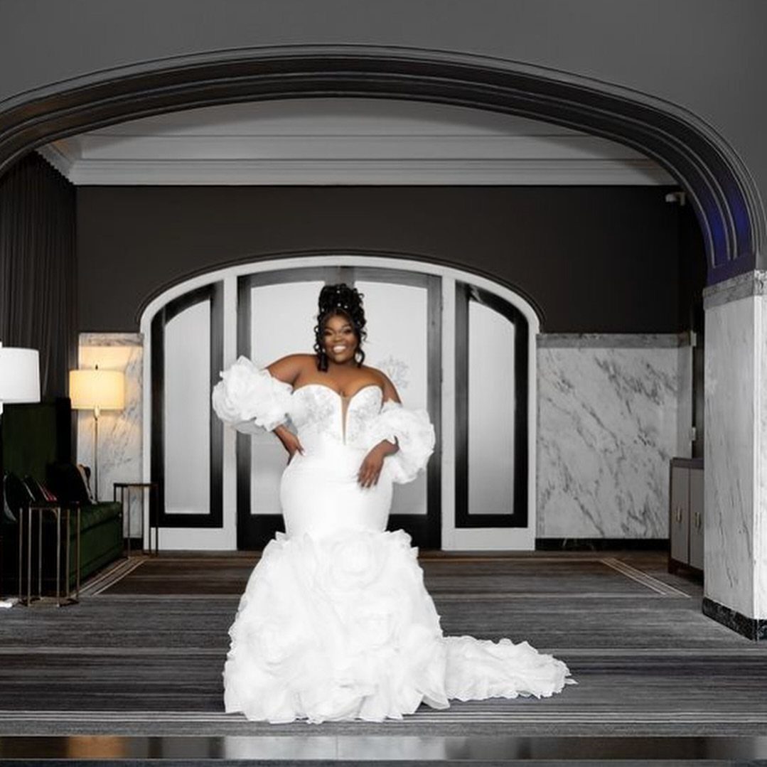 Curvy woman in a white mermaid wedding dress with voluminous ruffled details.